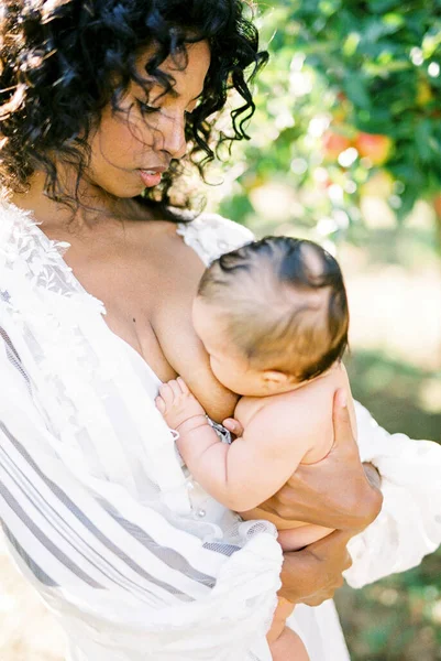 Vrouw borstvoeding haar pasgeboren baby in de tuin — Stockfoto