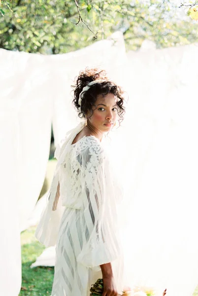 Γυναίκα με φόρεμα στέκεται κοντά στις λευκές κουρτίνες στον κήπο — Φωτογραφία Αρχείου