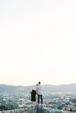 Kadın başını, dağa bakan taş bir duvara yasladı. Arka plan