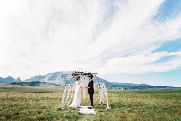 Se tenir debout sur un tapis blanc devant l'arche de mariage sur la pelouse — Photo