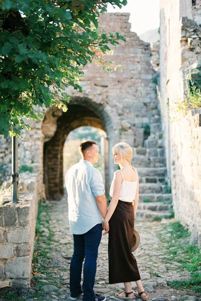 Erkek ve kadın kalenin taş duvarının yanında el ele tutuşuyorlar. Arka plan — Stok fotoğraf