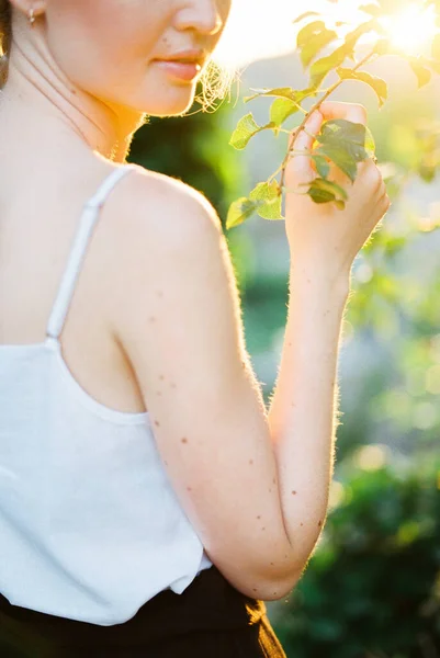 Mujer joven toca una rama verde en el jardín con la mano. Primer plano — Foto de Stock