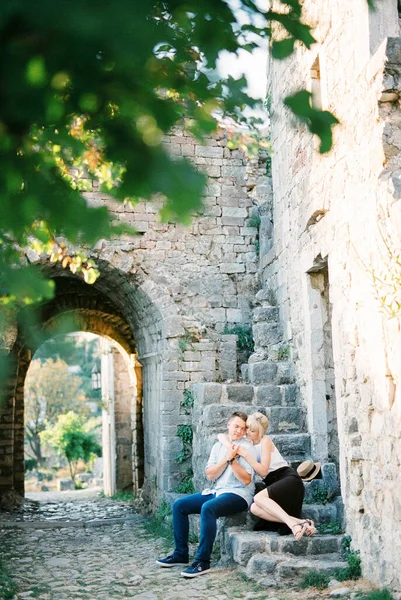 Kadın, kalenin taş basamaklarında oturan bir adama sarılıyor. — Stok fotoğraf