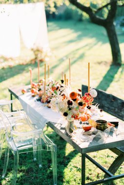 Bahçedeki sandalye ve bankların yanında mum ve ikramlarla dolu bir masa.