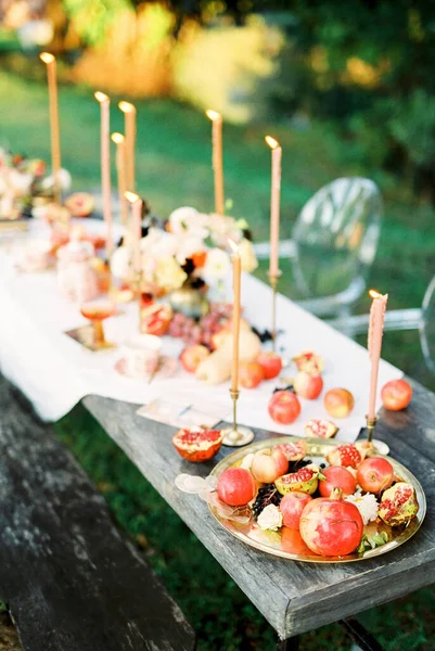 Wooden table with candles and treats stands in a green garden — Stock Photo, Image