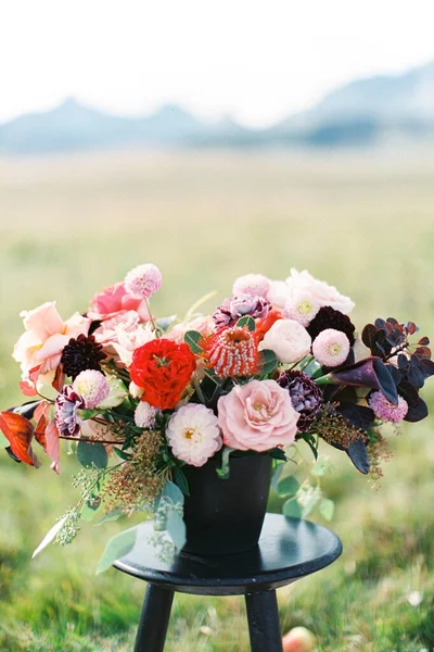 Svatební kytice ve váze stojí na stoličce na zeleném trávníku. Detailní záběr — Stock fotografie
