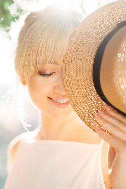 Gülümseyen kadın yüzünün yarısını şapkayla kapatıyor.