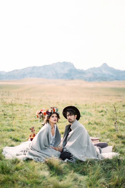 누런 잔디 위에 깔아 놓은 침구 위에 앉아 있는 신부와 신랑 — 스톡 사진