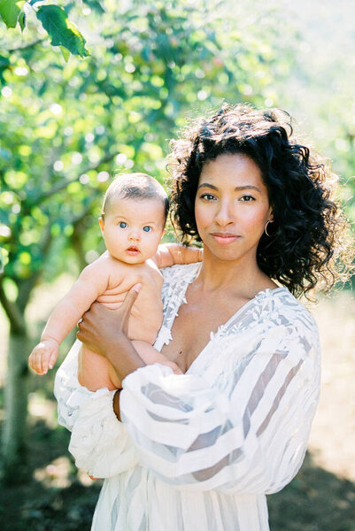 Woman with a baby in her arms in a green garden Stock Photo