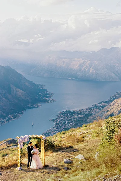 코토르 만 위에 있는 산에 있는 결혼식 아치에 앉아 있는 신랑 과 신부 — 스톡 사진