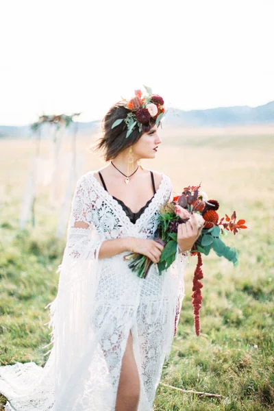 花の花束を持つ花輪の花嫁は、彼女の頭が横になってフィールドに立っている — ストック写真