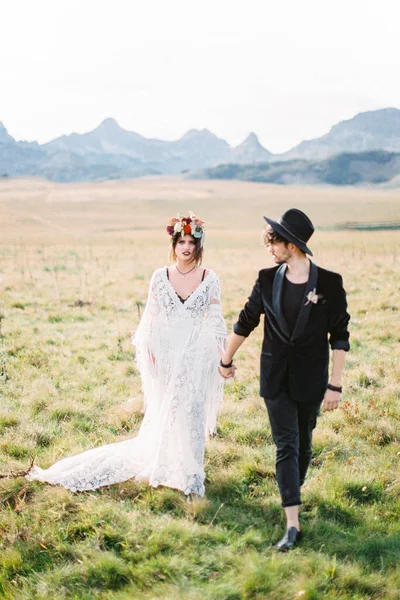 Noiva e noivo caminham pelo gramado de mãos dadas — Fotografia de Stock