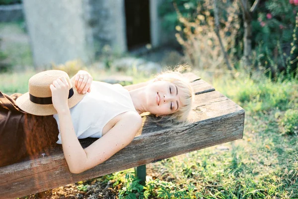 眼睛闭着的女人躺在木制长椅上 — 图库照片