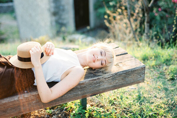 Woman with closed eyes lies on a wooden bench Stock Photo