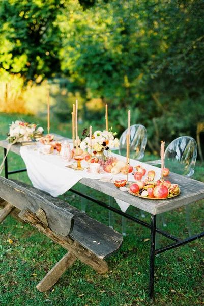 Deitado mesa com frutas e velas no jardim perto de um banco e cadeiras — Fotografia de Stock