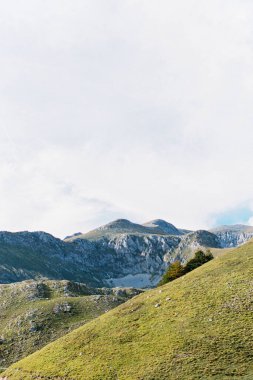 Bulutlu gökyüzüne karşı yeşil kayalık dağ sırası