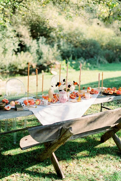 Dřevěný stůl s ovocem a svíčkami stojí v zelené zahradě — Stock fotografie