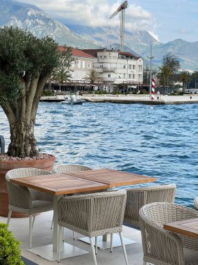 Wooden tables with wicker chairs on the pier by the sea overlooking the mountains. High quality photo
