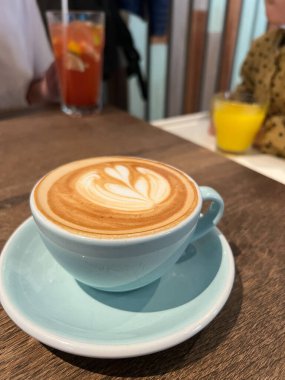 Köpük desenli bir bardak kapuçino masanın üzerinde duruyor. Yüksek kalite fotoğraf