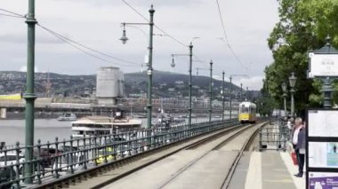 Sarı tramvay Tuna 'nın kıyısındaki bir durağa ulaşır. Budapeşte, Macaristan. Yüksek kalite 4k görüntü