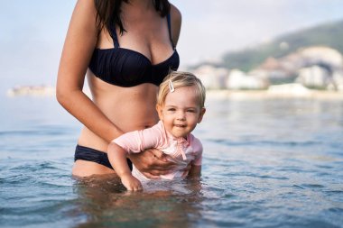Annem küçük bir kızı sığ sularda tutuyor. Yüksek kalite fotoğraf