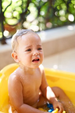 Küçük kız balkonda bir kase suyun içinde otururken sızlanıyor. Yüksek kalite fotoğraf