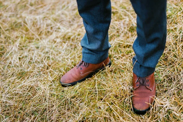 Men feet in brown shoes on dry grass. Close-up. High quality photo