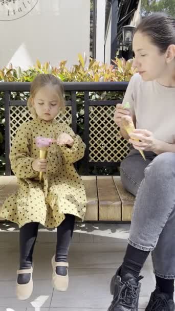 Anya Egy Kislányával Jégkrémet Eszik Spatulákkal Padon Ülve Parkban Kiváló — Stock videók