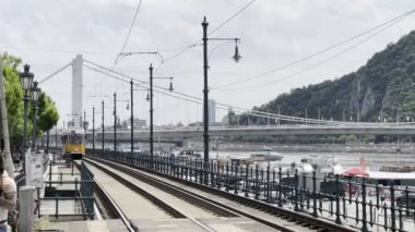 Tramvay, Tuna seti boyunca köprünün arka planına doğru ilerliyor. Budapeşte, Macaristan. Yüksek kalite 4k görüntü