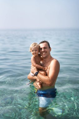 Gülümseyen baba ve denizde duran küçük kız. Yüksek kalite fotoğraf