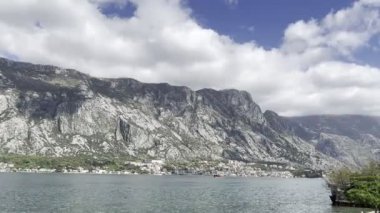 Tekne Kotor Körfezi boyunca dağların arka planına doğru yelken açıyor. Yüksek kalite 4k görüntü