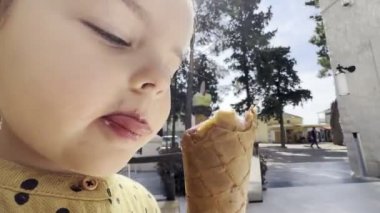Küçük kız gözleme külahında diliyle dondurma yalıyor. Yüksek kalite 4k görüntü