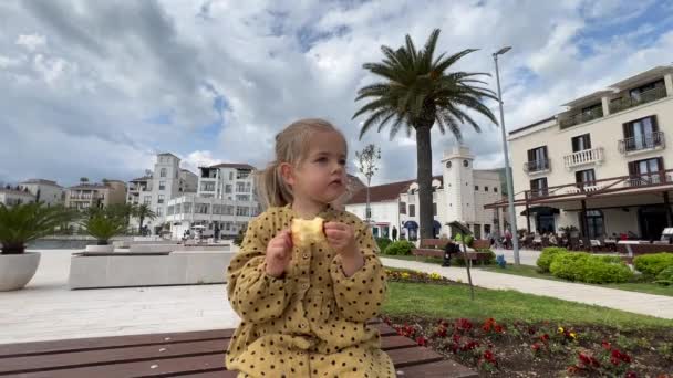 Little Girl Eating Apple While Sitting Garden Beautiful Houses High — Stock Video