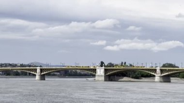 Yellow tram rides over the Margaret Bridge across the Danube. Budapest, Hungary. High quality 4k footage