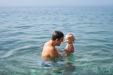 Babam kucağında küçük bir kızla yüzüyor. Yüksek kalite fotoğraf