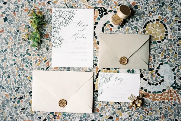 Wedding invitations next to the envelopes lie on a mosaic tile. High quality photo