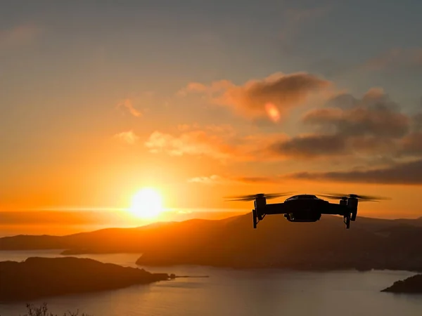 Drone hovers over the sea against the backdrop of mountains at sunset. High quality photo