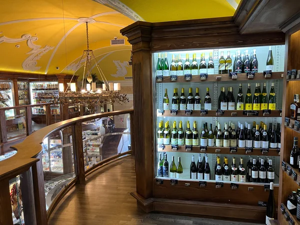 Bottles of wine are on the shelves in a glass cabinet in the store. High quality photo