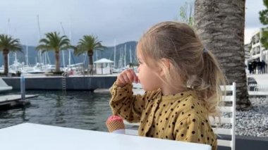 Little girl eating ice cream with a spoon. High quality FullHD footage