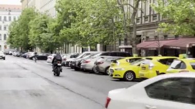 Motorcycle rides down the street past cars parked near buildings. High quality 4k footage
