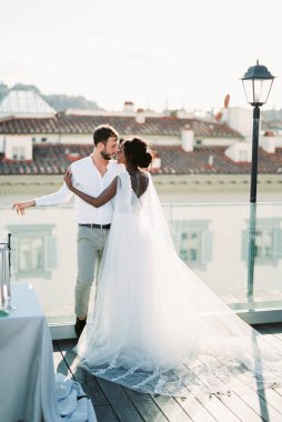 Bride and groom stand at the parapet on the roof of the building. High quality photo