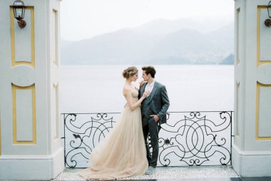 Bride and groom hugging between the columns on the embankment. High quality photo