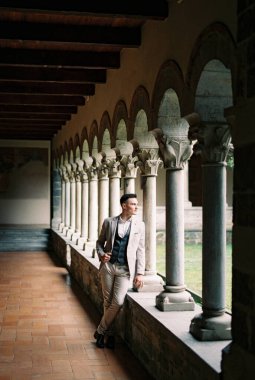 Man stands near a column on the terrace and looks out into the garden. High quality photo