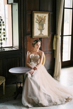 Bride sits at a table near the window of an old villa. Como, Italy. High quality photo