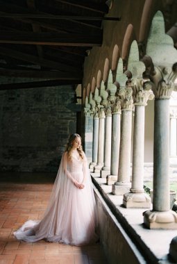 Bride stands near the columns on the terrace of an old villa. Lake Como, Italy. High quality photo