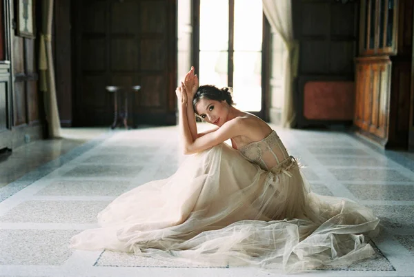 Bride sits on the floor in front of the window of an old villa. High quality photo