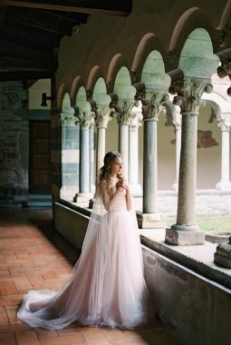 Bride stands with her hands clasped in prayer on the terrace of an old villa. High quality photo