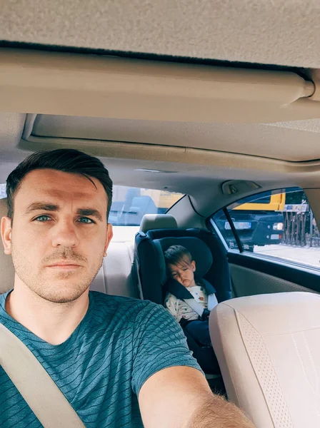 Dad driving a car with a small child in a child seat behind. High quality photo