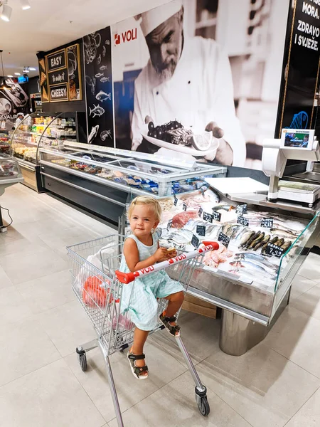 Little Girl Sits Cart Counter Fish Supermarket High Quality Photo — Stockfoto