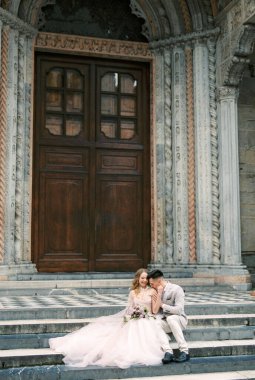 Bride and groom sit on the steps of the Church of Santa Maria Maggiore. Bergamo, Italy. High quality photo